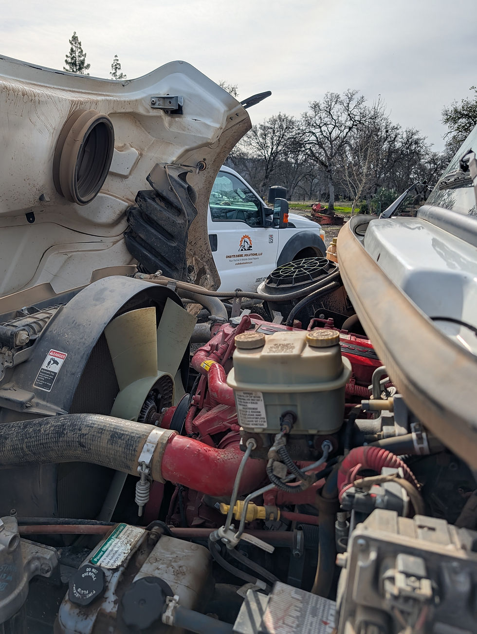 “Freightliner M2 dump truck with hood open showing diesel engine components and cooling sy