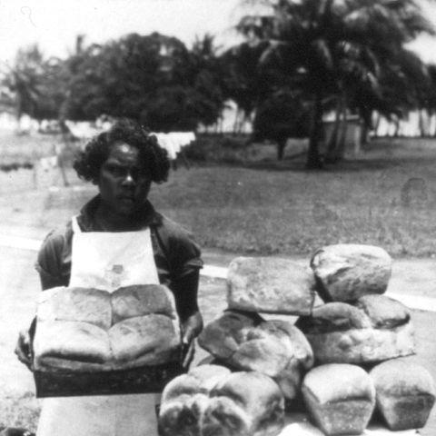 An Australian worker standing with a loafs of bread.