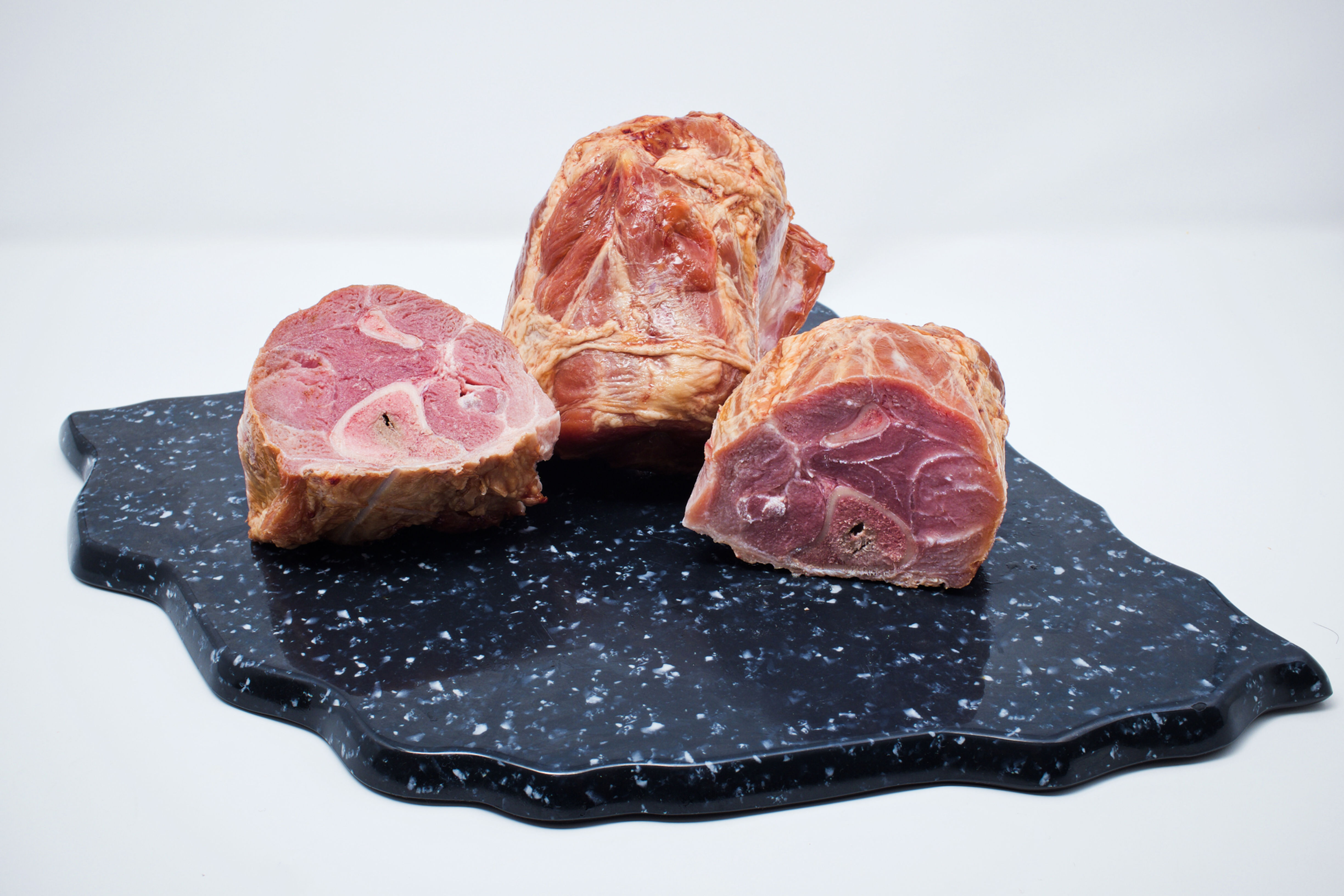 Smoked ham shanks on black cutting board.