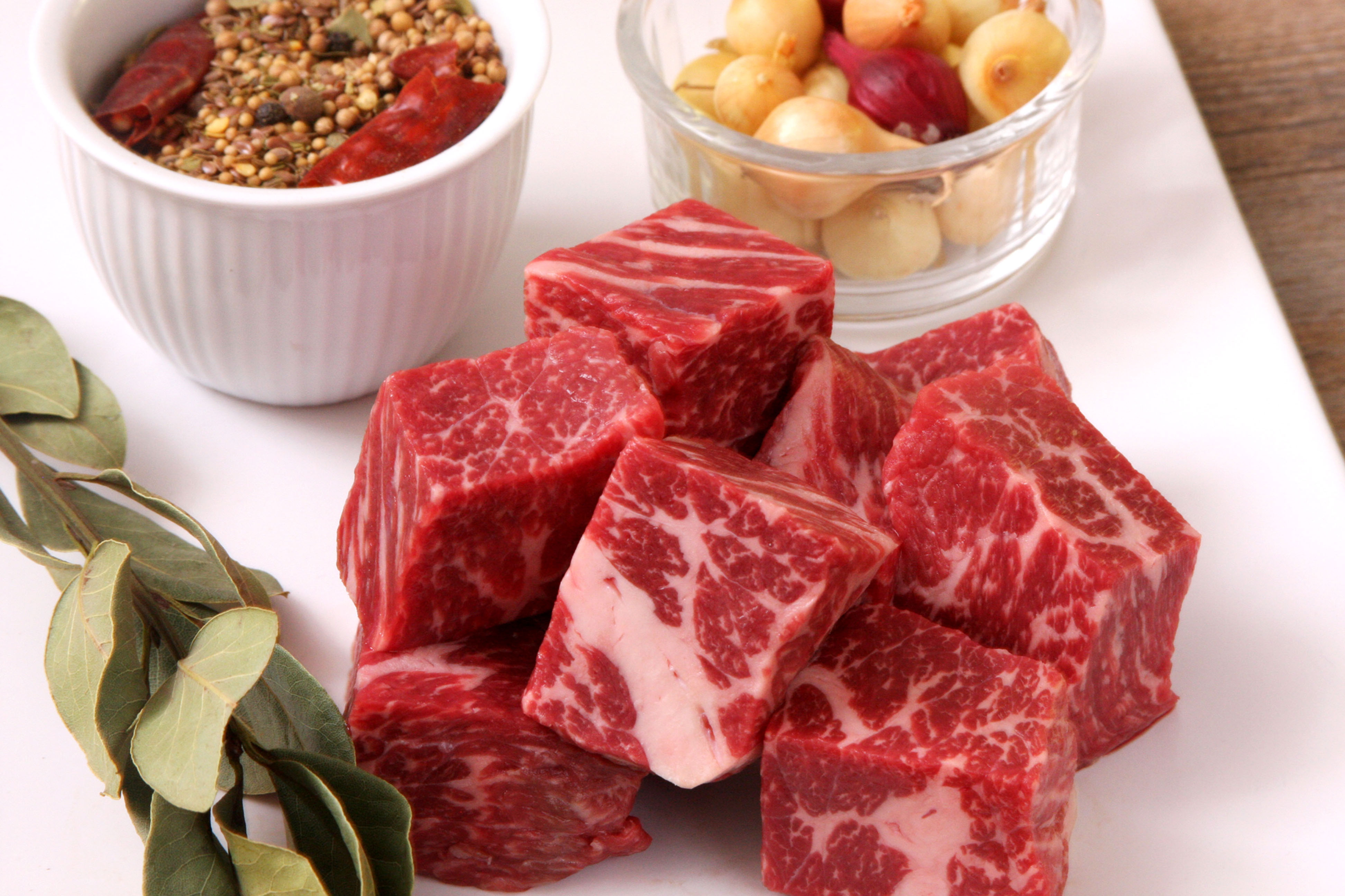 Raw Wagyu cubes with bowls of seasonings next to them.