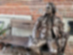 Young George Washington sitting on a bench along Duke St reflecting on his experience in the French and Indian War.