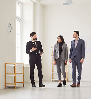 Realtor or estate agent guides couple through new property or apartment, exploring rent or
