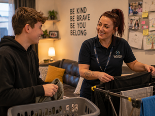 Residential support worker helping a young person with daily living skills in a Leicester children’s residential home during an evening routine.