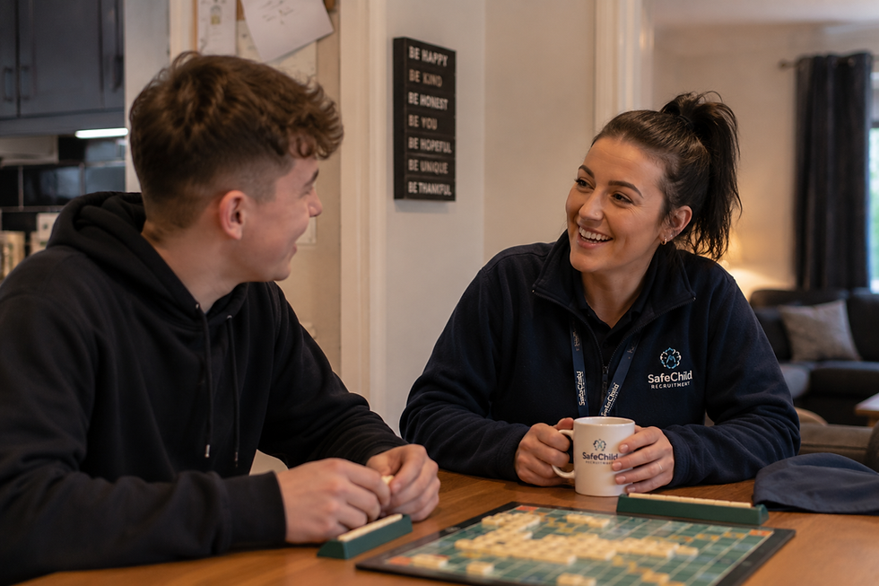Residential support worker playing a board game with a young person in a warm Wolverhampton children’s home during an evening activity session.