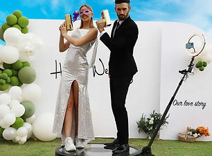 A couple poses joyfully in a 360 photo booth at their wedding