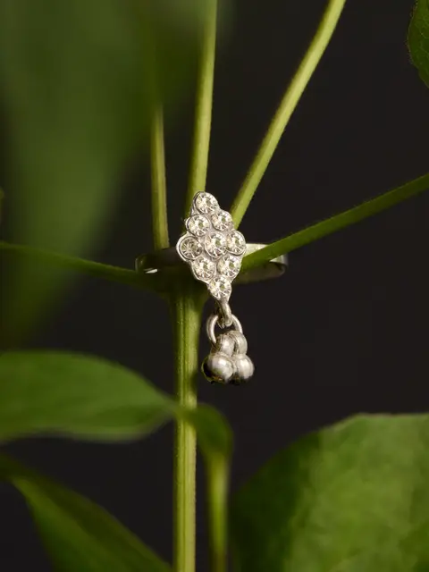 Boucle d'oreille en diamant sur une plante verte, fond noir, photographie Anne-Clotilde Obéniche
