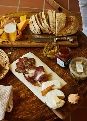 Grazing boards arranged on a wooden table with cheeses, olives, charcuterie and fresh strawberries.