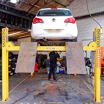 white hatchback raised up on an MOT ramp