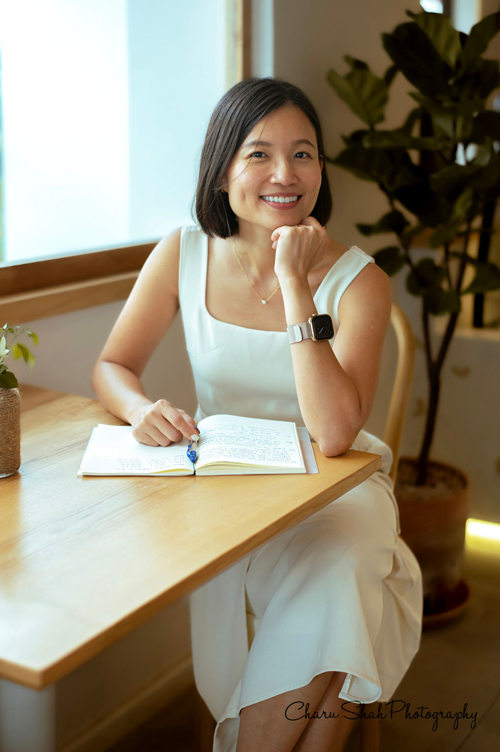Lady sitting and posing with a notebook on the table 