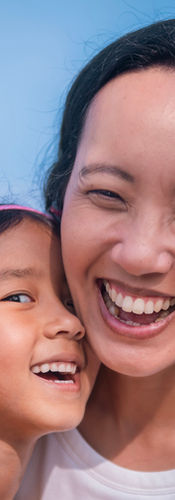 girl gives a kiss to her mother on the neck. They are both smiling and enjoying the moment