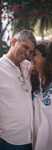 A couple share a candid moment between them. They are lightly embracing each other and have their foreheads touching while they smile