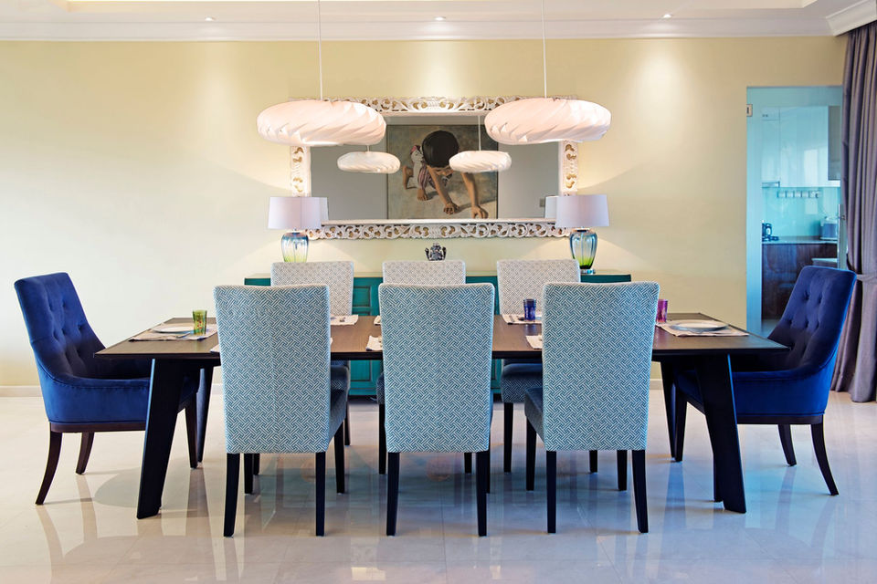 Dining room styled by a professional interior designer. Navy blue chairs with model chandeliers hanging from the ceiling