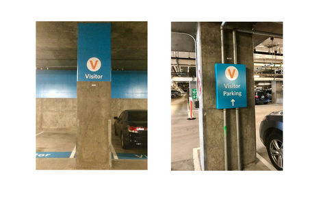 Two photographs of columns denoting visitor parking signage, including blue paint and “Visitor” label on concrete columns and custom fabricated metal signage to accommodate pre-existing piping.