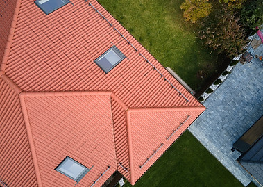 Closeup of attic windows on house roof top covered with ceramic shingles. Tiled covering o