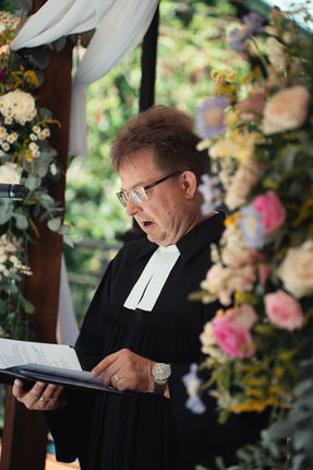 Wedding officiant reading beside colorful flowers
