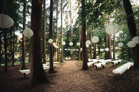 Forest wedding aisle decorated with white hanging lanterns