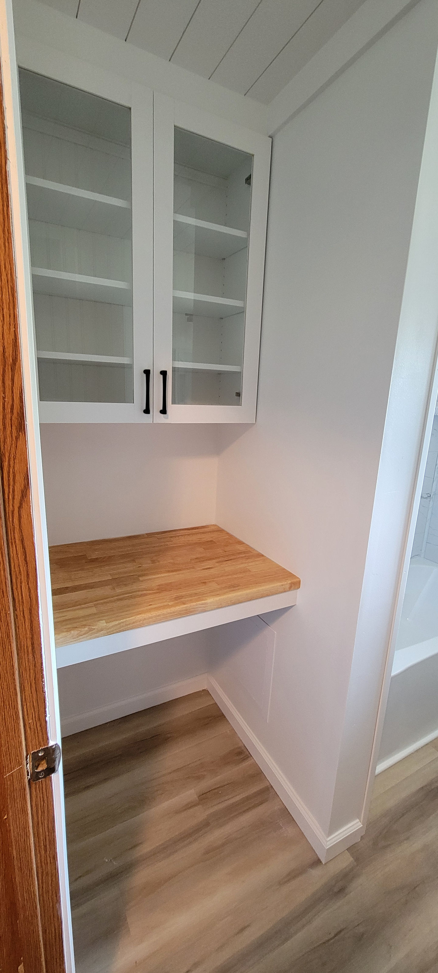 Small wooden countertop with white cabinets above.