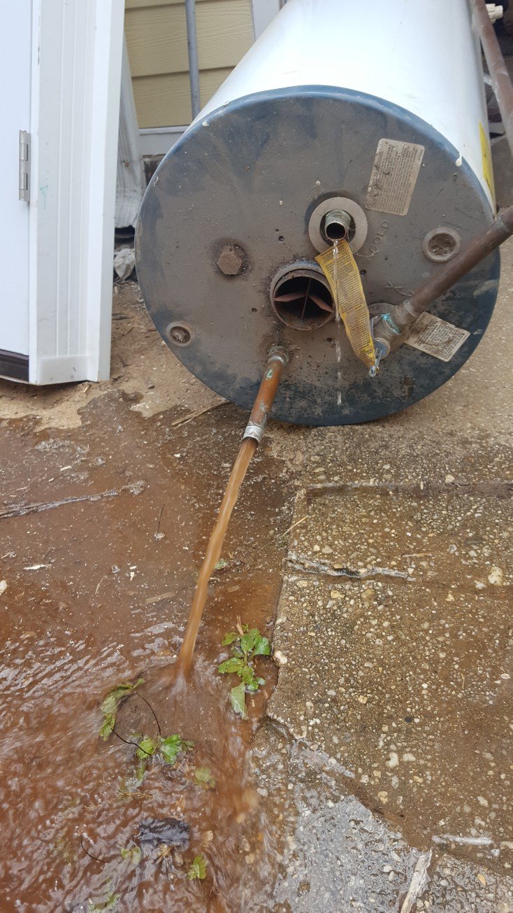 In the photo above you can see a water heater which is been removed prior to disposal. The water heater is being drained out onto the ground and the Water Runs Out in a deep red color. Sludge and sediment have built up in this water heater over the period of 15 to 20 years and it's likely that this water heater has not been properly and regularly serviced.