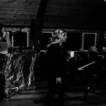 Denver DJ speaking into a microphone behind a DJ booth at an indoor event