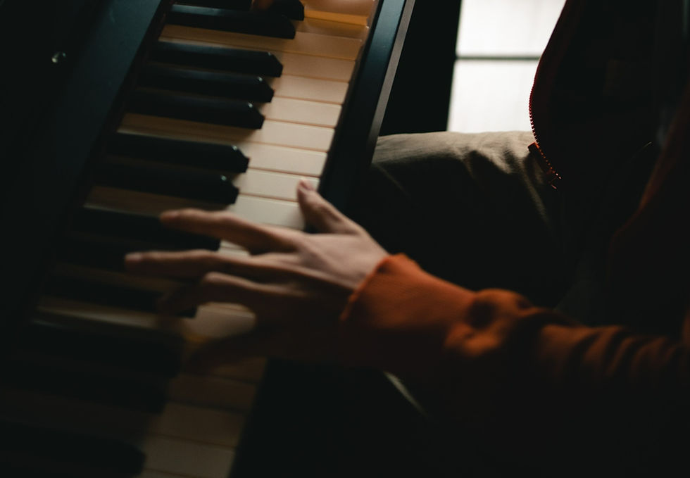 person improvising while playing an upright piano keyboard