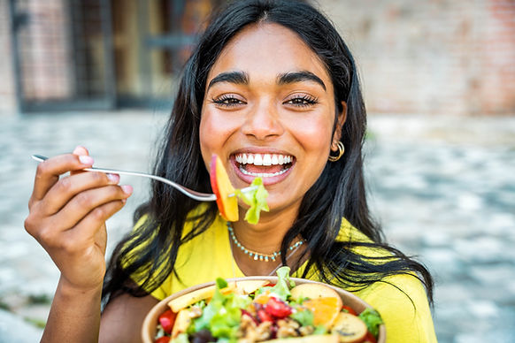 Smiling woman enjoying a fresh fruit and vegetable salad