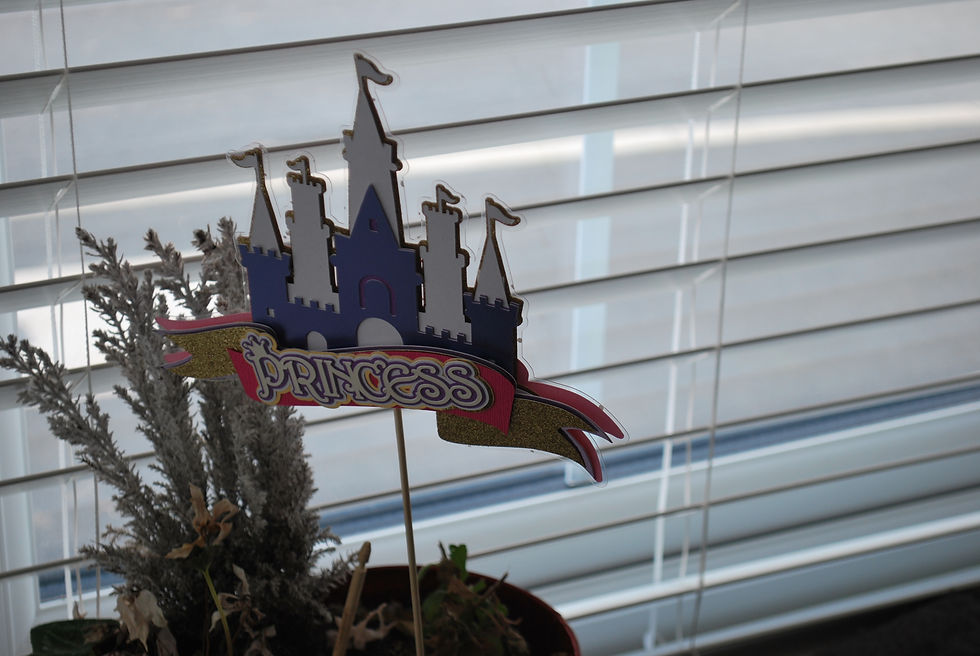 A wide shot of a purple and white princess castle cake topper featuring a gold glitter "Princess" banner.