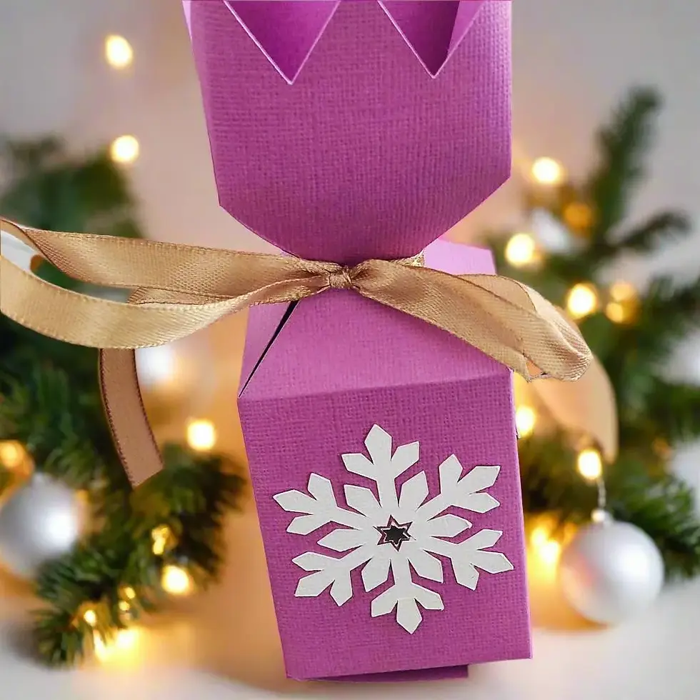 Close-up of a purple snowflake gift box tied with a gold ribbon, featuring a Christmas tree and lights.