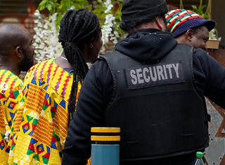 Security officer standing beside attendees at a community celebration