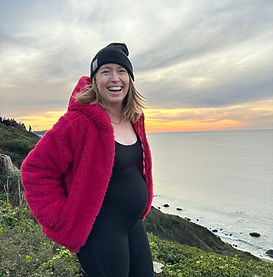 Jo, pregnant, smiling on the San Francisco coast at sunset