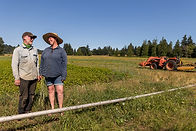 Genine and Colin Kirsop of Kirsop farm stand on their field with a tractor in Washington State