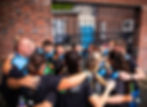 Group of people in workout gear huddle together, with a man in the front saying, "Hot HIIT Cardio".