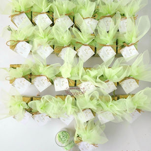 Bulk order of First Holy Communion return gifts wrapped in sage green net with jute twine and personalized gold thank-you cards, handmade peony candle favors by Candles with a K Bangalore