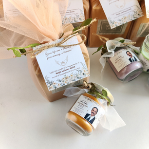 Close-up of a personalized memorial candle with photo label "In Loving Memory Ralph Anthony Smith," beside a peach tulle-wrapped remembrance gift favor