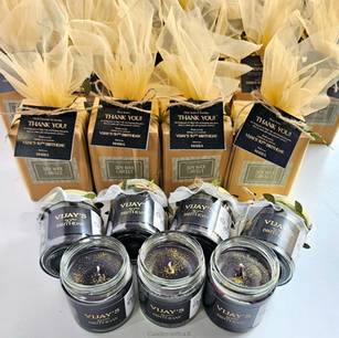 Custom 50th birthday favor jars with black soy wax and gold glitter displayed alongside matching cream net-wrapped gift boxes by Candles with a K.