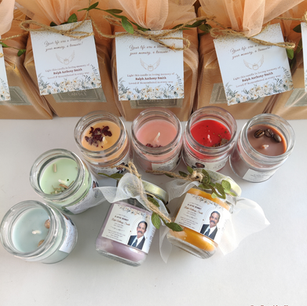 Assorted personalized memorial candles in multiple colors with photo labels reading "In Loving Memory Ralph Anthony Smith," alongside gold tulle-wrapped condolence favors