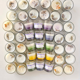 Rows of colorful, layered candles in votive glass jars