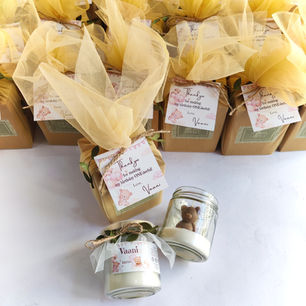 A beautiful arrangement of custom 1st birthday return gifts featuring teddy bear favor jar candles and matching cream tulle-wrapped gift boxes.