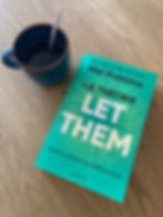 French edition of ‘The Let Them Theory’ by Mel Robbins beside a coffee cup on a wooden table.