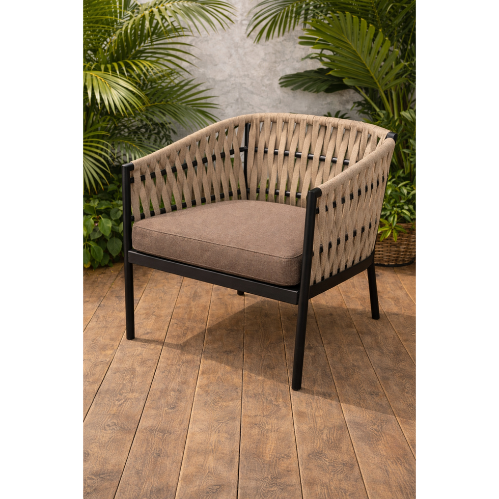Woven beige outdoor armchair with black frame on wooden patio floor.
