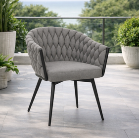 Stylish grey outdoor chair on balcony with ocean and green plants.