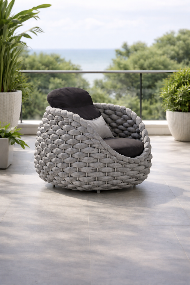 Round textured outdoor chair on balcony overlooking ocean.