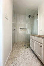 Luxury walk-in shower with frameless glass enclosure and marble herringbone tile floor by Maison Vue Home on the Emerald Coast