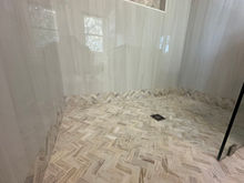 Custom bathroom remodel featuring marble herringbone shower floor and frameless glass enclosure by Maison Vue LLC on Florida’s Emerald Coast
