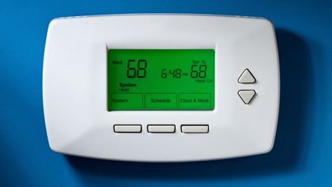 Homeowner checking a digital thermostat on the wall to diagnose a thermostat problem vs HVAC system issue in Somerset PA