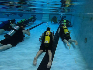 Beginner taking first discover scuba lesson with instructor in shallow water learning to breathe underwater