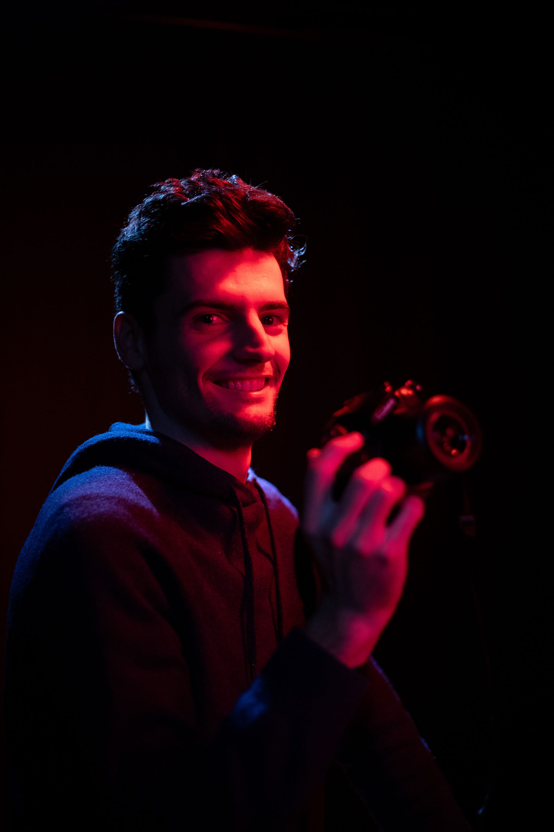 Portrait d'un jeune homme souriant, tenant son appareil photo