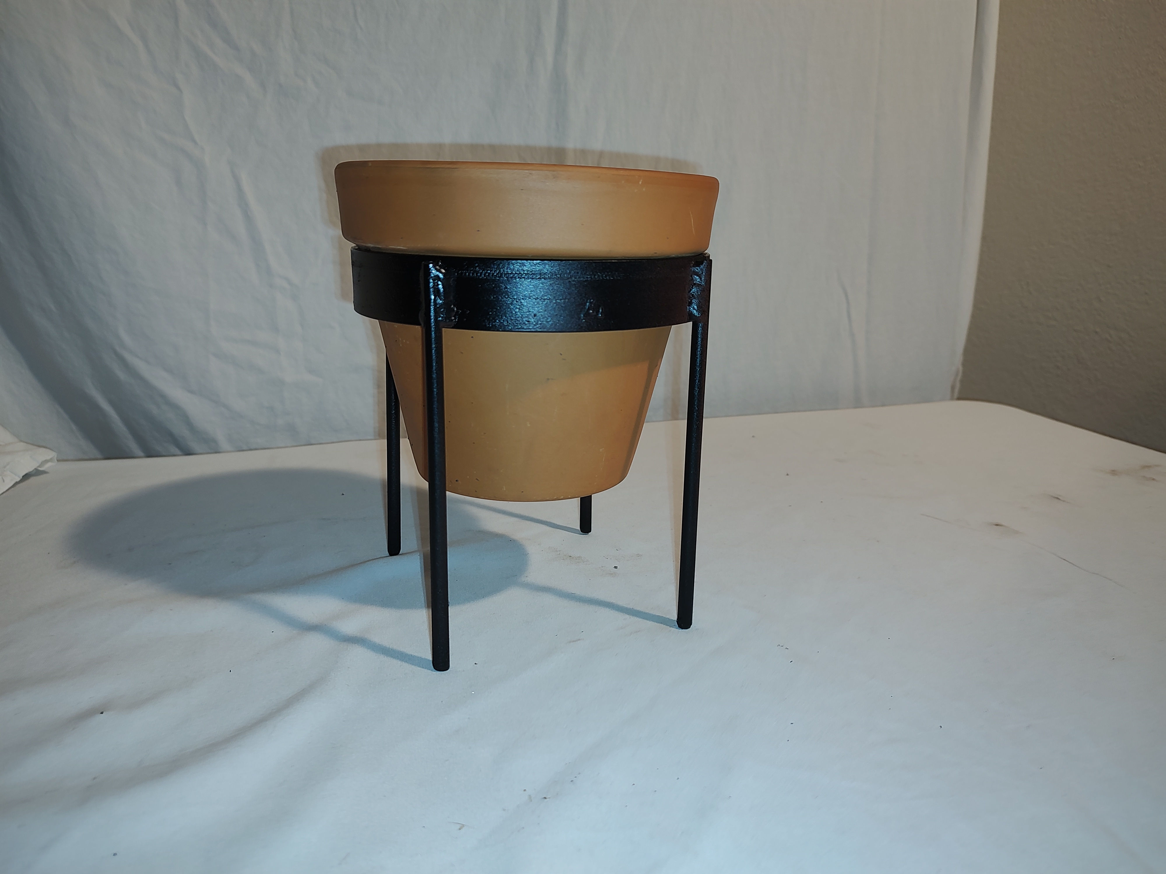 Front view of simple metal plant pot holder in black.