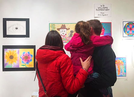 A family looks at original art on a white wall
