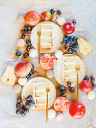 Individual cake slices surrounded by fresh fruit and macarons
