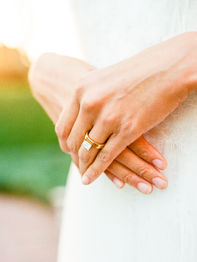 Clasped hands wearing a gold wedding ring